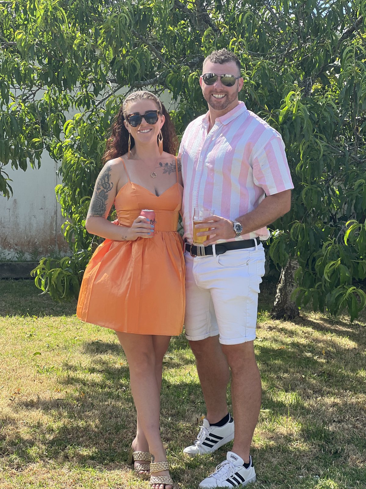 Dani in an orange dress with Alex on a summer lawn