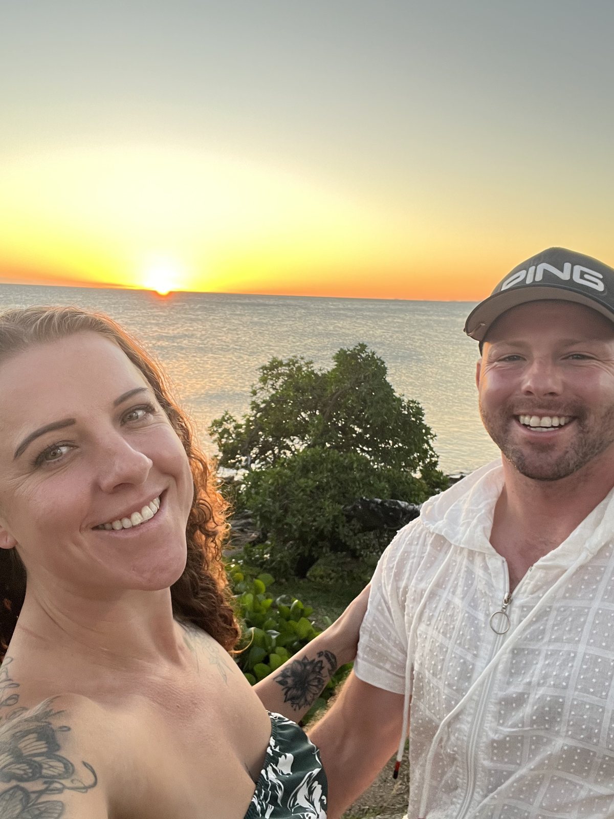 Dani and Alex taking a selfie as the sun sets over the sea