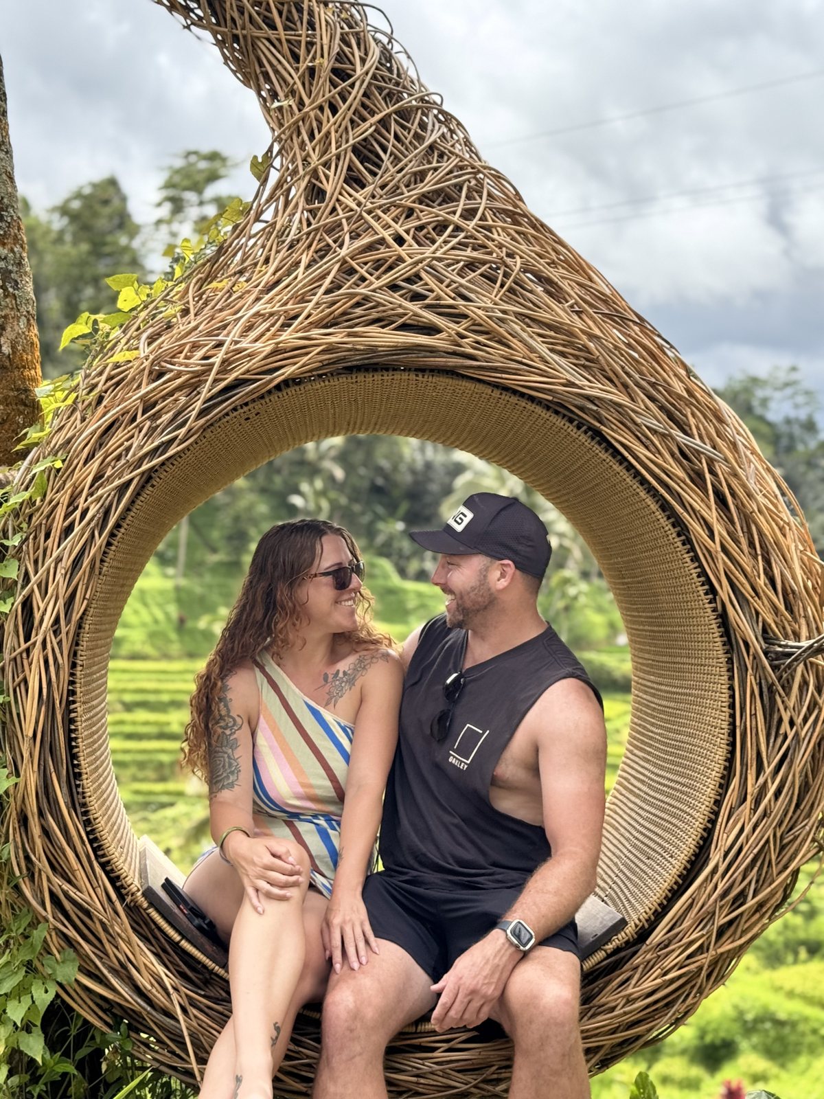 Dani and Alex sitting inside a woven nest swing